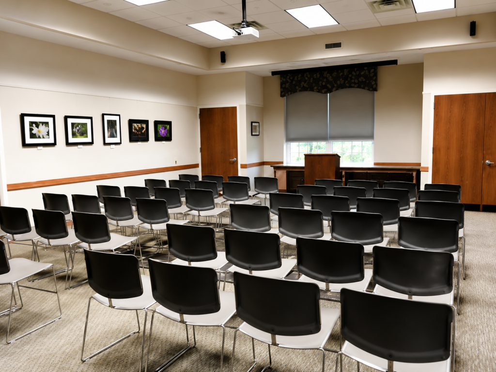 Empty chairs arranged in a meeting room with framed photos on the wall